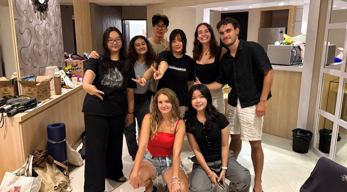 HOK-Studentin Elena sitzt lachend mit ihren internationalen Freunden in einem gemütlich bewohnten Zimmer in Indonesien.