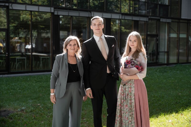 Drei HOK-Spondierende in festlicher Kleidung & Tracht am Campus. 