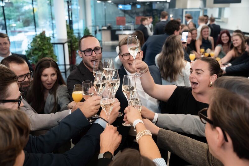 Glückliche Absolvierende stoßen nach dem offiziellen Festakt miteinander an.