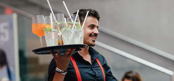 Servicekraft mit Tablett voller Cocktails bei Veranstaltung an der HOK.
