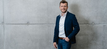 Person in Business-Outfit vor Betonwand an der HOK