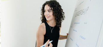 Studentin schreibt an einem Flipchart mit dem Thema Leadership an der HOK