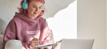 Studentin lernt mit Laptop, Notizbuch und Kopfhörern im Online-Unterricht von zuhause