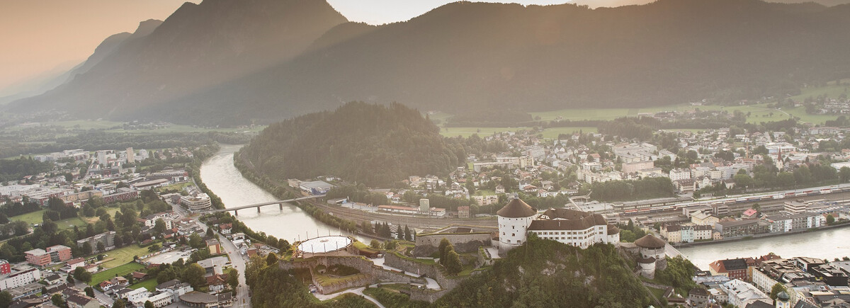 Luftaufnahme von Kufstein mit der Festung Kufstein, dem Inn und umliegenden Bergen bei Sonnenuntergang