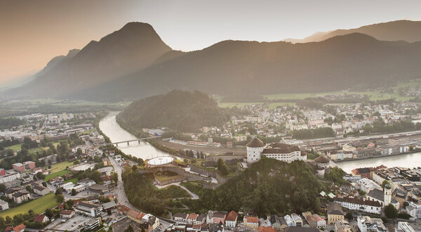 Luftaufnahme von Kufstein mit der Festung Kufstein, dem Inn und umliegenden Bergen bei Sonnenuntergang