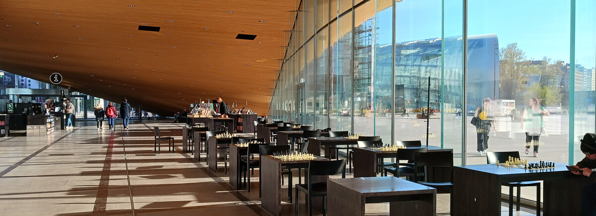 Eine Reihe von Stühlen und Tischen stehen neben einer großen Glasfassade in einer Halle.